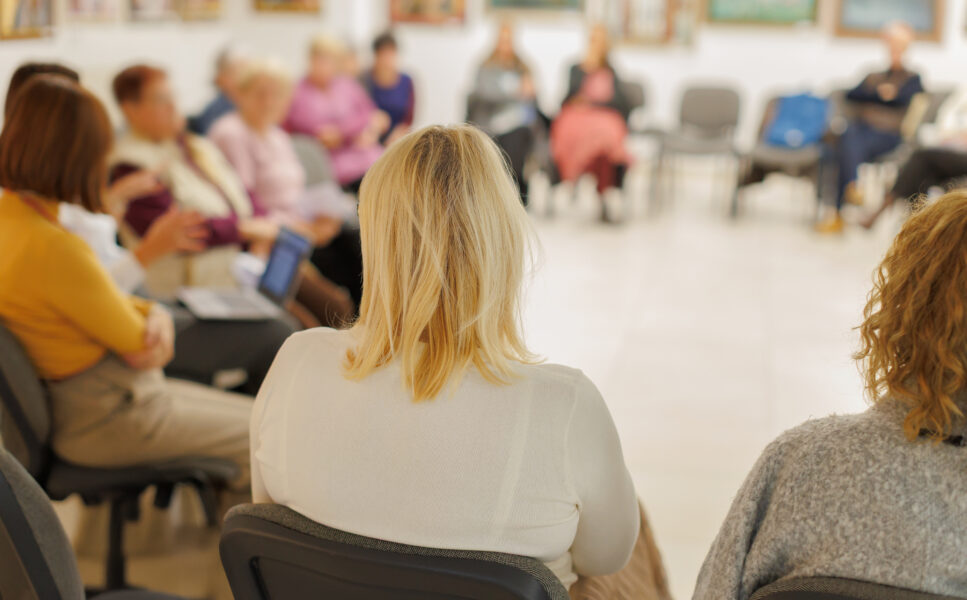 Group of women sitting in a circle during a meeting in a community center focused on discussion and sharing ideas